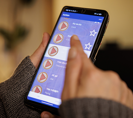 A person uses a Tlingit language learning app on a smartphone