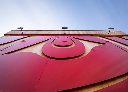 Upward view of a red Greatest Echo formline panel on the Sealaska Heritage Arts Campus