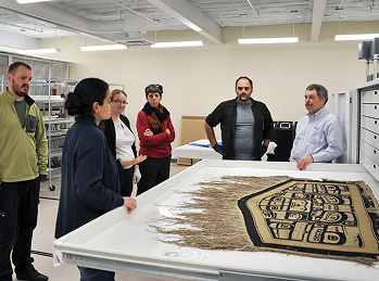 Researchers gathered around a Chilkat robe in the collections workspace