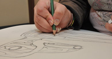 Student drawing a Northwest Coast formline design with a pencil