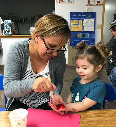 An educator helping a young child with a hands-on art activity