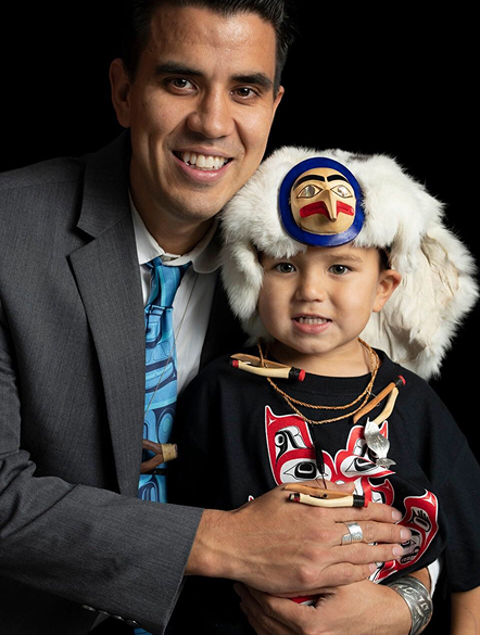 Benjamin Young holding a child dressed in regalia