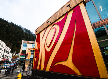 Red monumental formline panel on the Atnané Hít exterior