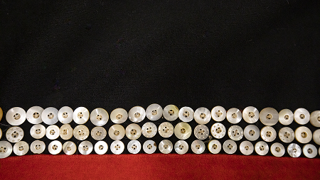 Rows of shell buttons sewn onto red and black wool