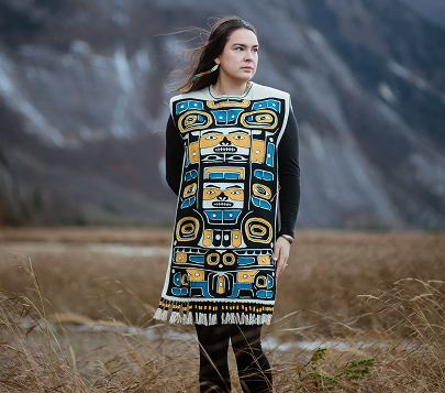 Artist wearing a Chilkat-style woven robe outdoors