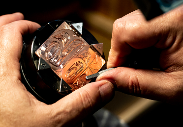 Hands engraving a Northwest Coast design into copper