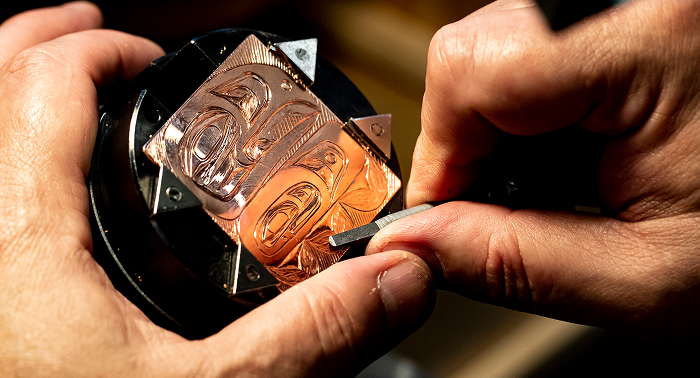 Hands engraving a Northwest Coast design into copper