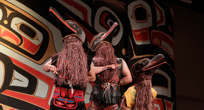 Dancers wearing carved masks and regalia perform at Celebration