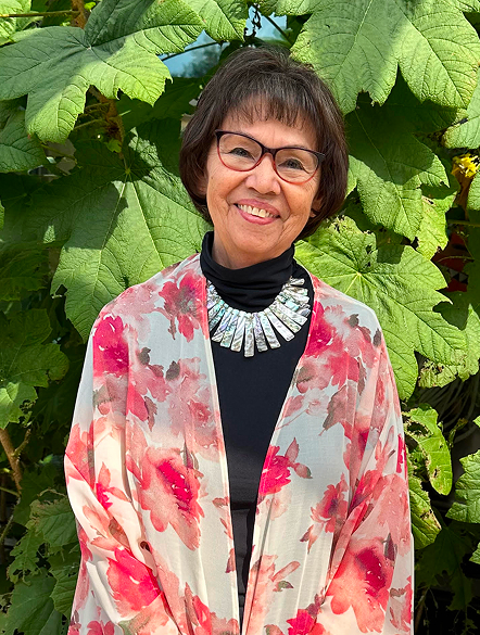 Donna May Roberts standing outdoors among large green leaves