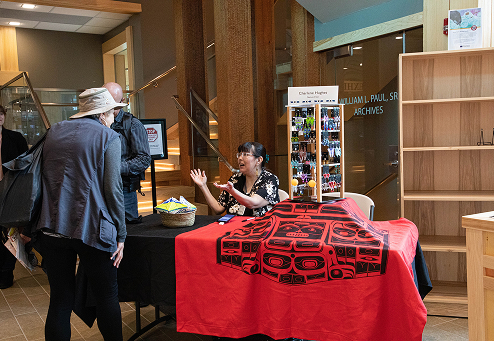 An artist speaking with visitors at a First Friday market table