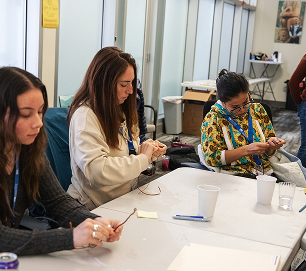 Educators make small cultural art projects around a classroom table
