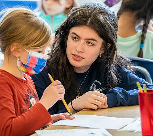 An educator helps a child complete a classroom activity