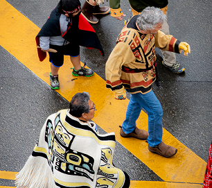 Parade participants dance across a downtown Juneau intersection