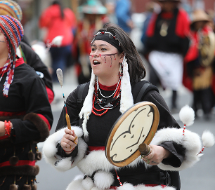 A drummer wearing black-and-white regalia sings during the Celebration parade