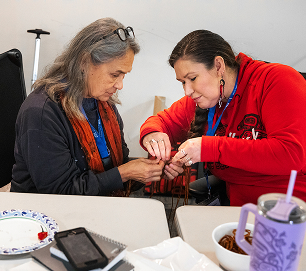 Two educators work together on a detailed cultural art project