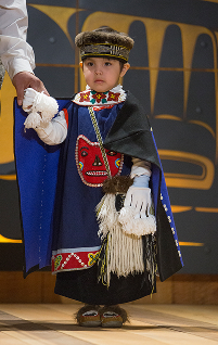 A young child models blue and black regalia at Celebration