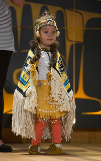 A young child models cream-colored regalia at Celebration