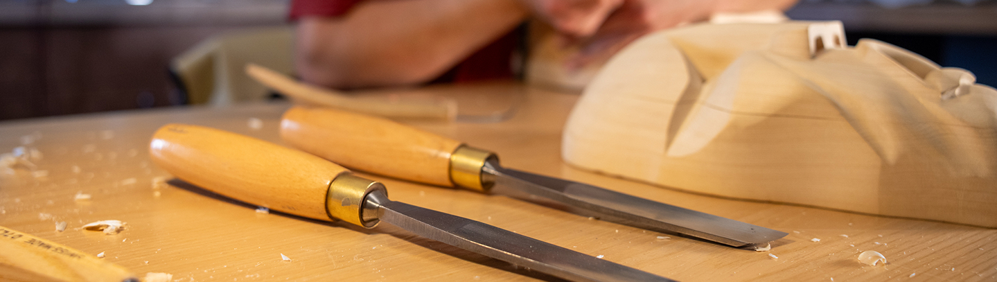 Woodcarving tools beside a Northwest Coast carving in progress