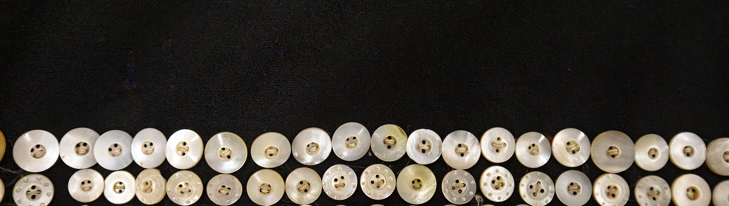Rows of mother-of-pearl buttons on black wool