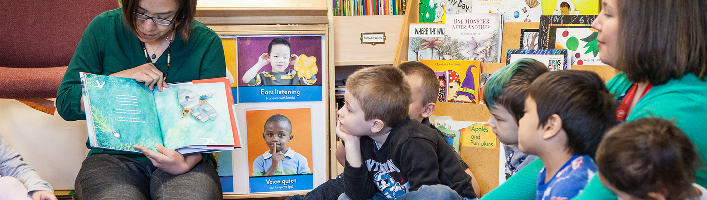 An educator reads a picture book with a group of young children