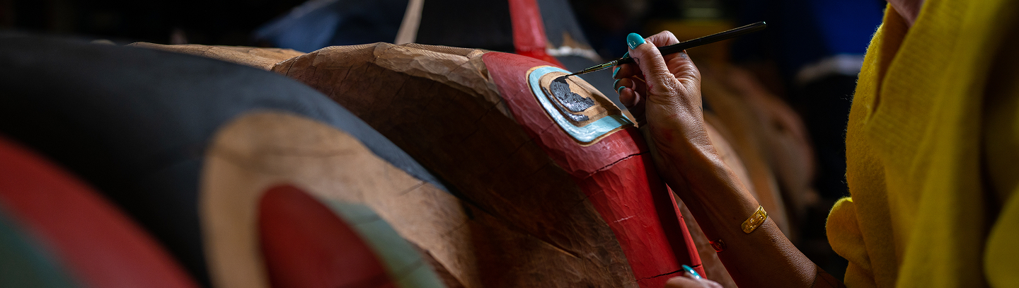 An artist painting a carved Kootéeyaa