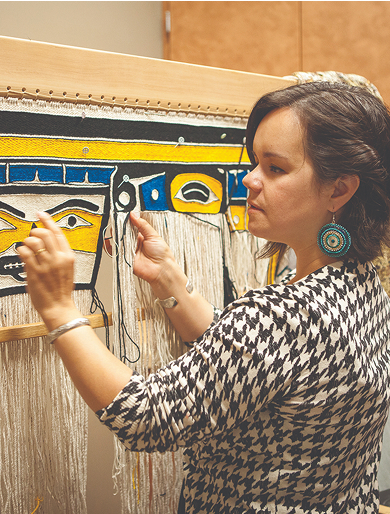 An artist weaving a Northwest Coast textile on a loom