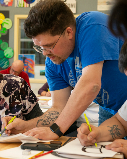 Instructor helping students draw Northwest Coast designs in an art class