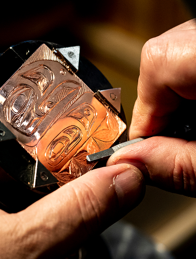 Hands engraving a Northwest Coast design into copper
