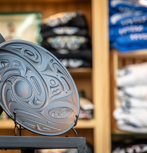 A carved circular Northwest Coast artwork displayed in the Sealaska Heritage Store