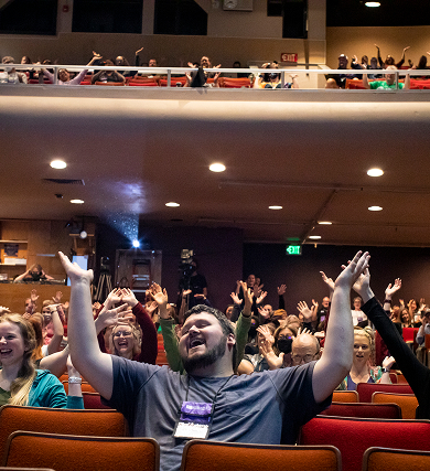 Conference attendees raising their hands in an auditorium