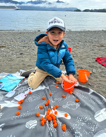 A young child taking part in a Baby Raven Reads beach activity