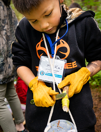 A Raven Writes student preparing a harvested plant outdoors