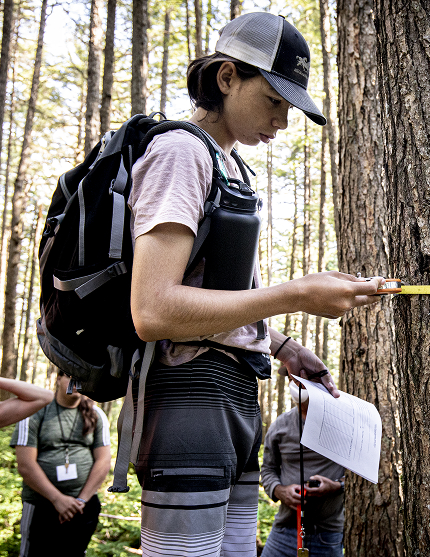 A Career Pathways student measuring a tree during an outdoor field activity