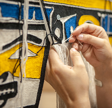 Artist sewing a Northwest Coast textile by hand