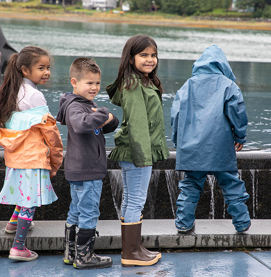 Children gathering outdoors beside the water during a cultural camp