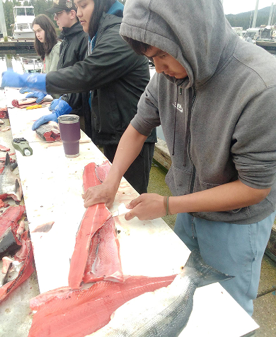 A student preparing salmon during a Cultural Warriors activity