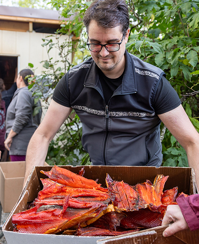 A Cultural Warriors participant carrying traditionally prepared salmon