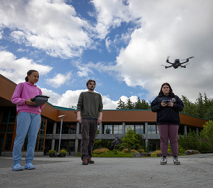 Three students operating a drone outside an Indigenous Science Academy building
