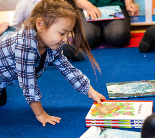 A child reaching for Baby Raven Reads books