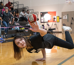 An athlete reaching for a suspended ball while balancing on one hand