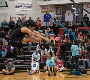 An athlete competing in a broad jump before spectators