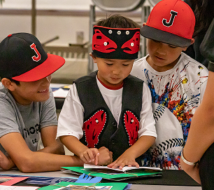 Three students reading together during a Raven Writes activity