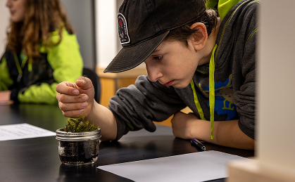 Student examining a plant specimen during a hands-on science activity