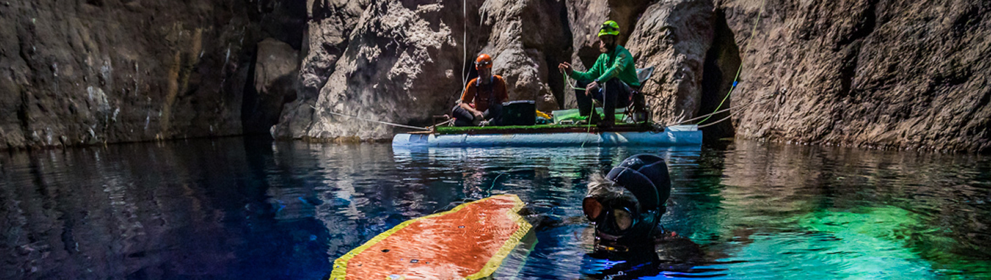 A diver and researchers documenting a carved panel in a flooded cave