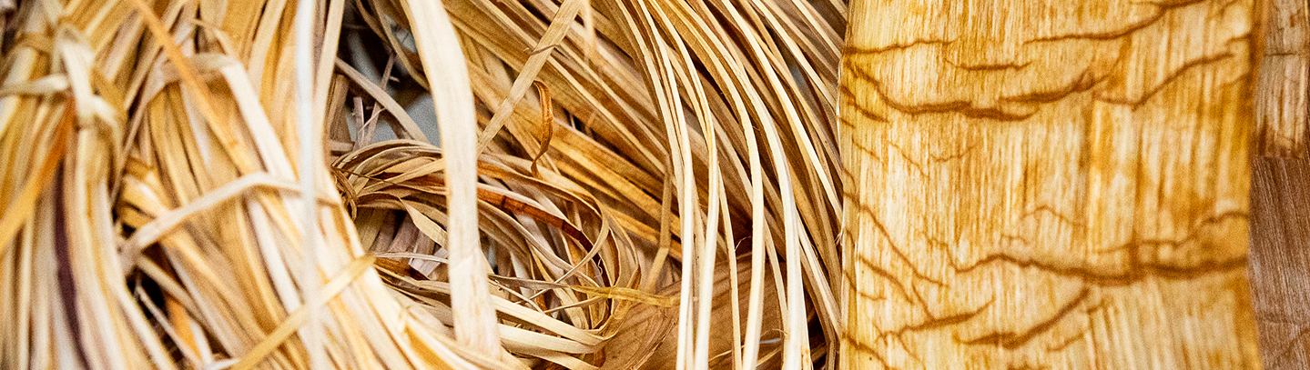 Close view of woven plant fibers beside carved wood