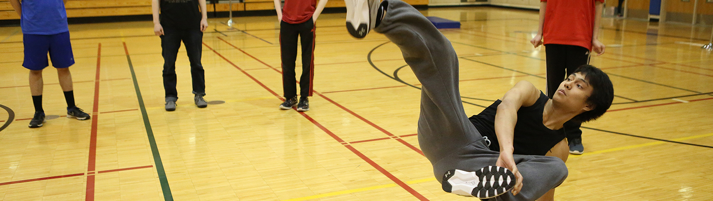 An athlete performing a high kick during Traditional Games in a gymnasium