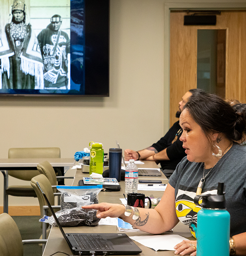 A researcher speaks during a meeting about black seaweed while historic photographs are shown