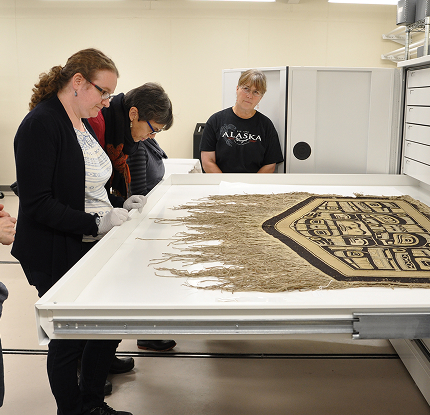 Museum staff examining a woven Northwest Coast robe