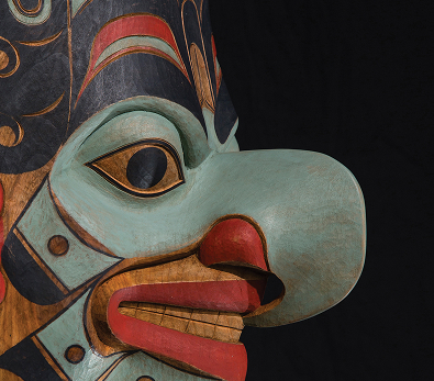 Detail of a carved and painted Northwest Coast mask against a dark background