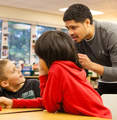 An educator working with elementary students during a Raven Writes program